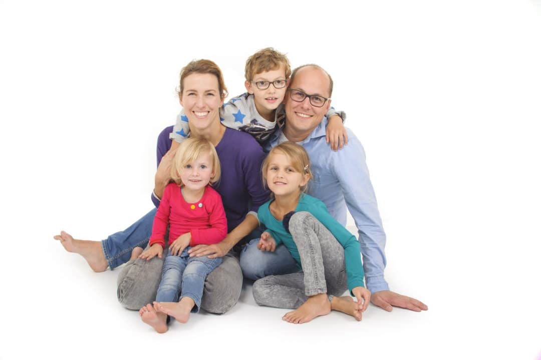 Gezinsfoto van een gezin met drie kinderen op een lichte achtergrond