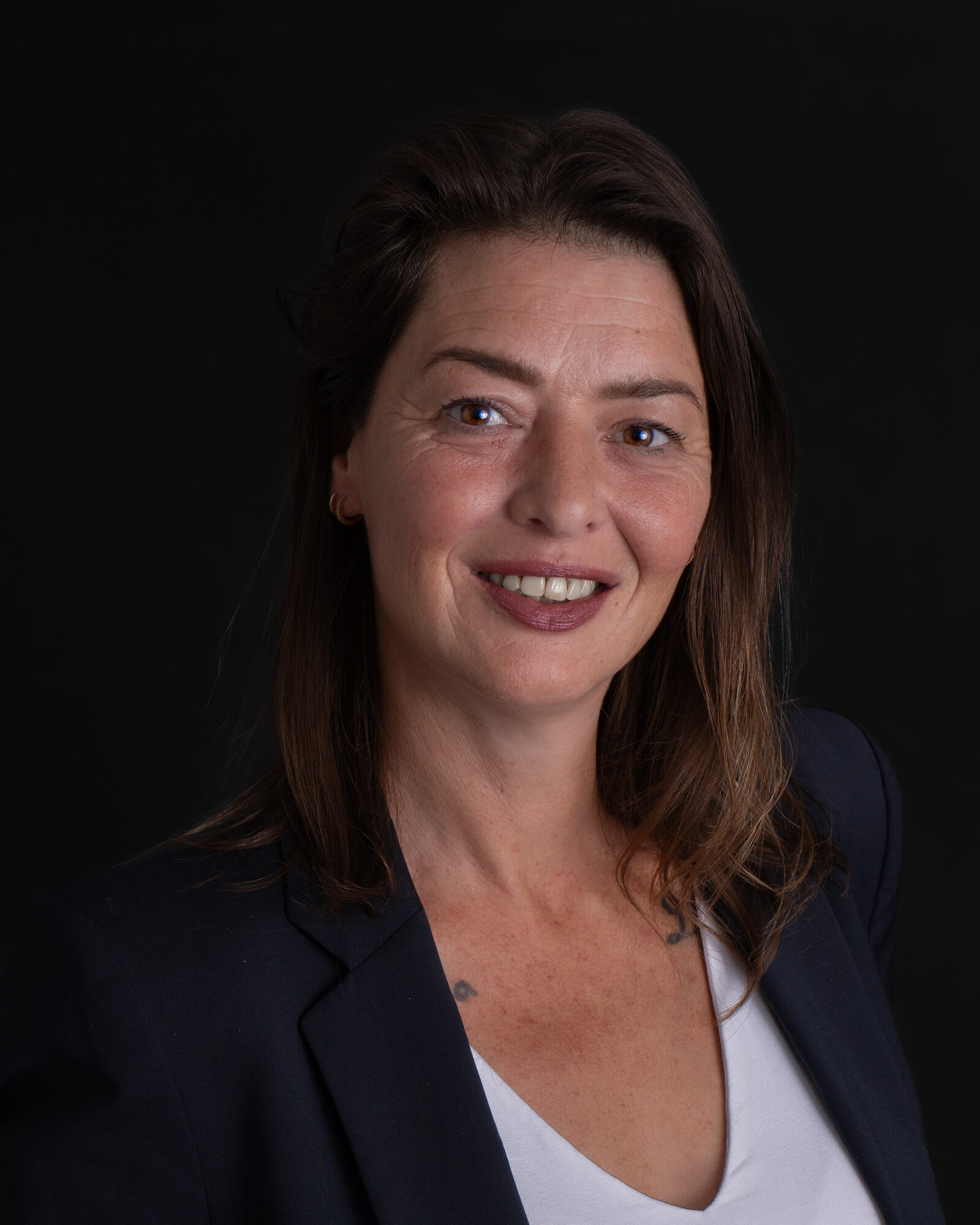 Close-up portret van Desiree van Virtuo Office Support met glimlach op donkere achtergrond, brandingfotoshoot bij Studio Shootable